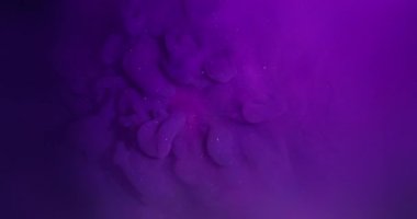 Akan mürekkep. Sıvı sıçraması. Odaklanmamış mor neon rengi ışıl ışıl ışıl parıldayan nemli doku soyut pembe arka planda yüzüyor..