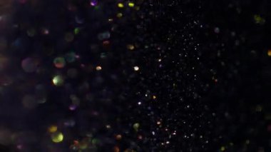Dikey video. Bulanık parıltılar. Bokeh ışığı. Soyut sanatın koyu siyah zemininde sönük sarı altın mavisi parıltı.
