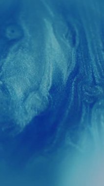 Dikey video. Görüntü parıltısı yağı. Parlak boya akışı. Mavi beyaz çok renkli sıvı parıldayan sıvı parlayan su soyut bokeh ışık arka planında hareket ediyor.