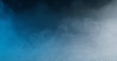 Bokeh buharı. Duman bulutu. Odaklanmamış mavi beyaz sisli desen renk mürekkep girdabı su akışı soyut koyu siyah arkaplan üzerinde yüzüyor.