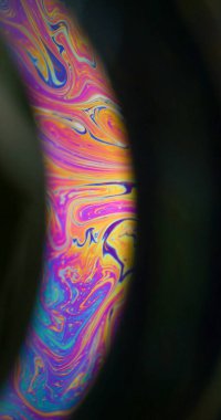 Gökkuşağı yağı. Boya karışımı. Çok renkli, yuvarlak, benzinli sıvı pigment siyah zemin. Soyut bulanık mor turuncu mavi parıltı sıvısı.