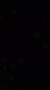 Dikey video. Işıl ışıl parlıyor. Lazer ışınları. Beyaz renk parıl parıl parlayan parlak ışık parıldıyor soyut karanlık arka planda hareket ediyor.