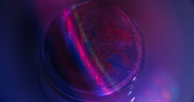 Gökkuşağı alevi. Hafif emülsiyon. Soyut neon arkaplanda sızan mavi pembe renkli yuvarlak mürekkep damlacıkları..