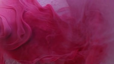 Dikey video. Pürüzsüz sis. Boya sızıntısı. Havadar pembe sanat damlası sıvı girdap dök yüzeyi düz olmayan beyaz kristal yüzeyde bulanık arkaplan.
