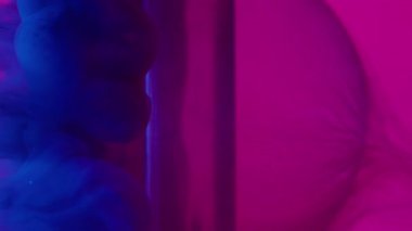 Dikey video. Duman sıçratma boyası. Top arka planda. Soyut pembe mor yaratıcı sanat üzerinde yüzen odaklanmış neon mavisi duman yuvarlak dokusu.