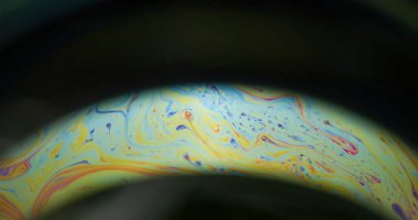 Yanardöner sabun. Gökkuşağı kemeri. Renkli yuvarlak mercek boyası, siyah arka planda kaotik boya akışı. Sarı mavi gece bulanık soyut ışık.