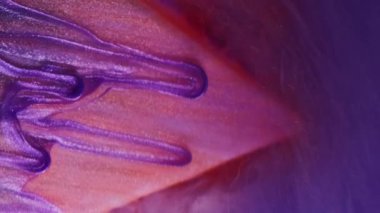 Dikey video. Mürekkep dök. Parıltı damlıyor. Mor, turuncu üçgen yüzeyine renk buharlı suda düşüyor. Soyut arka planda çözünmüş..