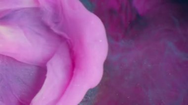 Dikey video. Işıldayan sıvı. Parlak dalga. Pembe boya damlaları düşen cam tırtıklı küre. Yüzen lüks mavi boya soyut su bulanıklığı koyu arkaplan.