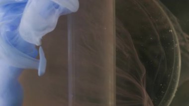 Dikey video. Yuvarlak sıvı. Boya bulutu. Odaklanmamış mavi renk su ıslak doku akışı soyut sanat üzerinde yüzen koyu siyah arkaplan.