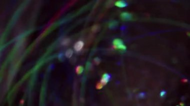 Bulanık çelenk. Parlak arkaplan. Girdap çok renkli, kırmızı parçacıklar parlıyor. Lens yanıp sönüyor. Sanatın koyu siyah soyutlaması üzerinde hareket ediyor..