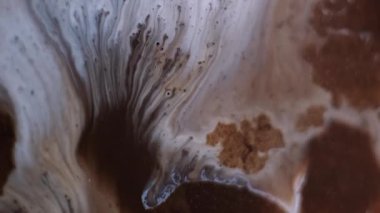 Karışık su sıçratma. Sıvı dökülmesi. Soyut arkaplanda hareket eden sıvıdaki kahverengi renkli kimyasal mermer parçacıkları çözünmüş..
