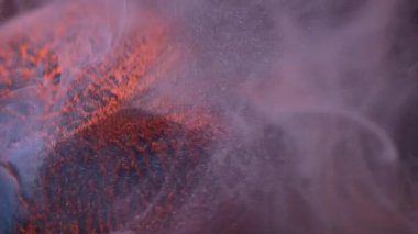 Dikey video. Haze bulutu. Duman akışı. Suda yüzen gri parlak mürekkep peçesi. Elmas yüzeyinde kayan turuncu toz boya soyut arkaplan.