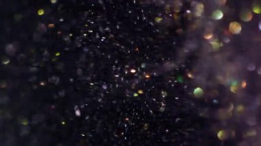 Dikey video. Yağ sıvısı. Parlak soyutlama. Odaklanmamış altın sarısı flaşlar açık renk su parıltısı sıvı koyu siyah arkaplanda sızıntı yapıyor.