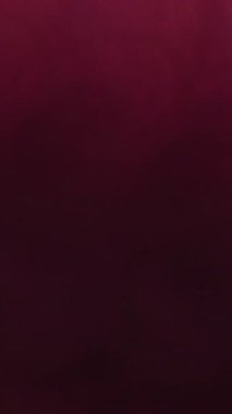 Dikey video. Bulanık soyut duman. Boya akışı mürekkebi. Dumanlı kırmızı renkli sıvı görkemli ışıl ışıl parlayan sis dokusu koyu açık arkaplanda kıvrılıyor..