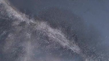 Köpüklü şeker. Parıltı akıyor. Su taneciklerinin nemli dokusunda çözünmüş mor renkli boya soyut arkaplana yayılıyor..