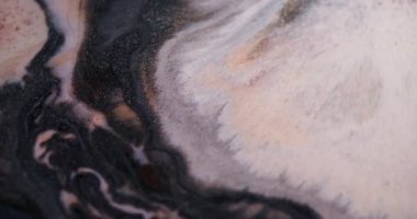 Sıçrama sıvısı. Akan boya. Odaklanmamış beyaz bronz renkli su koyu siyah parçacıklar soyut arkaplanda yayılıyor.