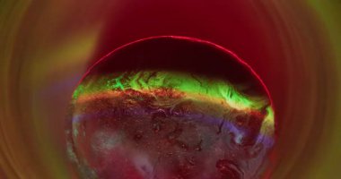 Neon dairesi. Parlak bir sıçrama. Soyut arkaplanda yüzen sıvı kimyasal gökkuşağı parçacıklarında çözünmüş sarı kırmızı renk boyası.