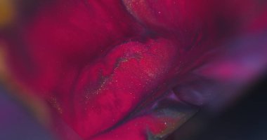 Sıvı dökülmesi. Parıldayan mürekkep. Odaklanmamış pembe renkli parlak sıvılar soyut neon bokeh arka planına yayılıyor..