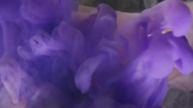 Dikey video. Puf boyası. Odaklanmamış dalga. Mor mürekkep dumanı sıvıda. Sanatsal girdap patlaması soyut arkaplan.