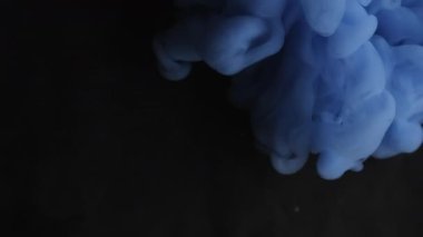 Haze mürekkebi. Mistik duman. Siyah yüzeye mavi bulut spreyi döküldü. Suyun soyut arka planında renk üfürüğü bulanık pigment patlaması.