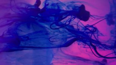 Dikey video. Neon mürekkebi. Cam kristal. Floresan mavi duman pigmenti elması döküyor. Pembe parlak sanat eseri arka planda renk değiştiren su lensi.