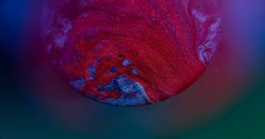 Mürekkep dök. Renkli karışım. Odaklanmamış kırmızı neon yuvarlak doku akan damlacıklar parlayan su soyut mavi arkaplan üzerine yayılıyor.