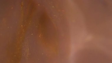 Mürekkep akışı. Köpüklü boya. Odaklanmamış sarı turuncu renkli kimyasal su parlatıcısı soyut sanat eserlerinin arka planında sıvı damlatıyor..