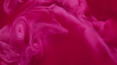 Boya sıçraması. Sis dalgası. Odaklanmamış kırmızı pembe renk sıvı partiküller kimyasal duman akrilik madde soyut arkaplanda dönüyor.