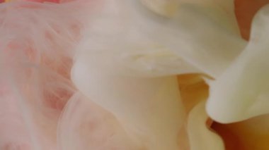 Dikey video. Çiçek arkaplan. Boya sıçraması. Odaklanmamış pembe bronz renkli su gülü soyut parlak sanat dalgasındaki nemli doku dalgasını karıştırır..