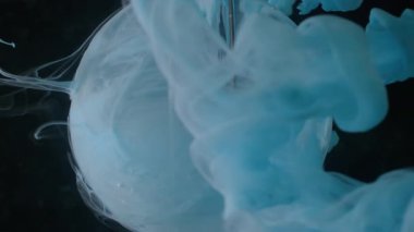 Dikey video. Küre boyası. Sıçrama akışı. Odaklanmamış mavi renk buhar deseni sıvı şeffaf yuvarlak şekil damlası soyut koyu siyah arkaplan üzerine.