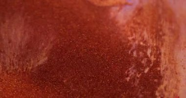 Sıçrama sıvısı. Parlak mürekkep parçacıkları. Odaklanmamış turuncu bronz renk, akrilik sanat arka planında akan ıslak parlak doku..