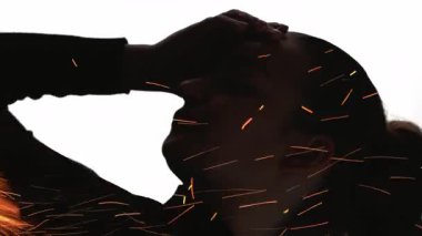 Dikey video. Endişeli siluet. Duygusal çöküntü. Ateş, beyaz tenli, bitkin bir kadının karanlık çifte pozlama profilinde hareket kıvılcımına yol açar.