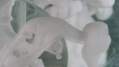 Dikey video. Sis boyası. Küre damlıyor. Odaklanmamış beyaz renk dokusu tozu soyut arkaplan üzerinde yüzen şeffaf yuvarlak sıçratır.