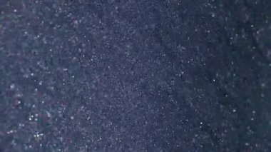 Kum mürekkebi. Parlak yüzey. Gri menekşe çözünmüş akış boyası ışıldayan metal parçacıkları dökülüyor. Parlak akış dokusu soyut arkaplan.