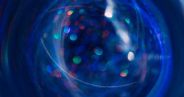 Parlak ışık. Bokeh ışını. Odaklanamayan mavi turuncu renkli parlak mercek soyut koyu siyah arkaplanda daireler çiziyor..