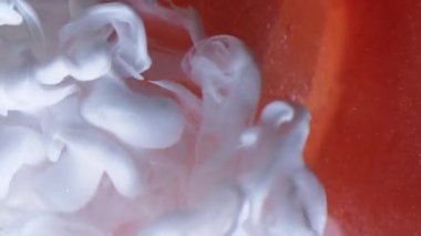 Dikey video. Pürüzsüz sis. Boya spreyi. Beyaz mürekkep dumanı portakal rengi pırıltılı elmasa damlıyor. Soyut bulanık arkaplan dökülüyor.