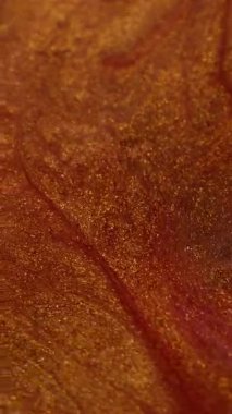 Dikey video. Parlak lav. Fantezi sıvısı. Turuncu bakır akışı, parlak parlak boya, parlayan sıvı sanat parçacıkları. Metal tozu akışı soyut odaklanmış arkaplan.