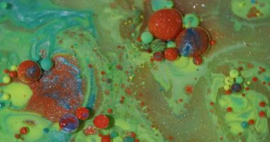 Akışı kes. Renk sıvısı. Odaklanmamış yeşil mavi parlak mürekkep köpükleri soyut arkaplanda parlayan turuncu pigmentler..