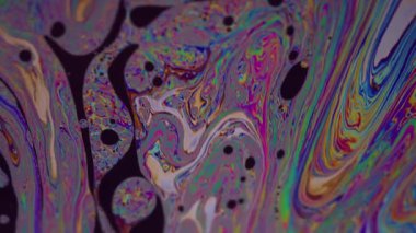 Gökkuşağı sıvısı. Mürekkep sıvısı. Bulanık yeşil pembe mor yağ lekeleri soyut koyu siyah arkaplanda yüzen sarı mavi doku.