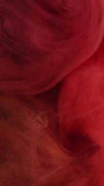 Dikey video. Duman kırmızı. Canlı bir duman. Küçük parçacıklarla değiştirilebilir sisli soyut arkaplan. Bulanık boya peçesi suda eridi..