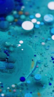 Dikey video. Boya akışı. Kabarcık emülsiyonu. Mistik mavi beyaz su karışımı çok renkli damlalar patlıyor. Dalga dökümü dokusu soyut arkaplan.