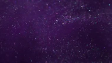 Bulanık pullar. Mürekkep sıvısı. Mor parçacıklar suya parlak pigmentler döküyorlar. Parıldayan soyut kozmik bulut patlaması arka planda parlıyor.