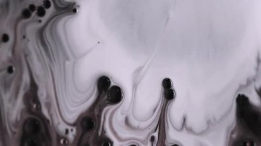 Damlama dokusu. Boya karışımı. Odaklanmamış beyaz süt rengi mürekkep köpüğü su kabarcığı sıvı damlaları soyut sanat eserine dökülüyor koyu siyah arkaplan.