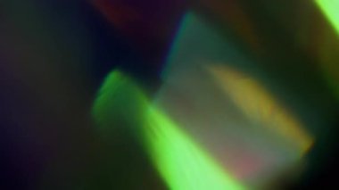 İşaret fişeği. Bulanık ışık merceği. Soyut koyu siyah arkaplan üzerindeki sönük mavi yeşil çoklu renk spektrumu yanardöner dokusu.