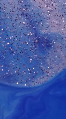 Dikey video. Akrilik kütle. Boya karışımı. Parıldayan metal parçacıkları mavi sanatsal suda yüzüyor. Soyut odaklanmış nem arkaplanı.