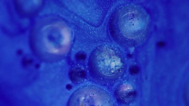 Akış dokusu. Odaklanamayan mermiler parlıyor. Işıl ışıl parlayan parlak sıvı mavi renkli parıldayan kabarcıklar soyut bokeh hafif arka planda hareket ediyor.