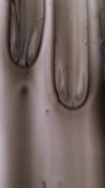 Dikey video. Sanat damlaları. Mürekkep damlaları. Gri siyah çözünmüş sıçrama dokusu. Karmaşık sıvı akışları soyut monokrom grunge arkaplanı dökülüyor.