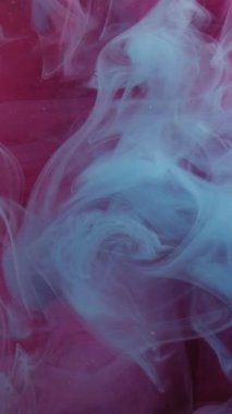 Dikey video. Çok renkli duman. Dalgalı sis. Işıldayan suyun soyut arka planında ince mavi girdaplar akıyor. Odaklanamayan mistik boya akışı.