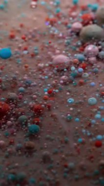 Dikey video. Yağ pigmenti düşüyor. Mürekkep patladı. Renkli kabarcıklar sanat suyunda çözünür. Yaratıcı sıvı karışımı soyut arkaplan bulanık parçacıkları .