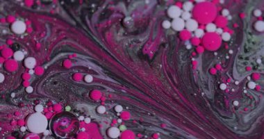 Petrol dökülüyor. Akrilik boyalı su. Bulanık pembe mor renk soyut yaratıcı arka planda yüzen parlak lekeler..